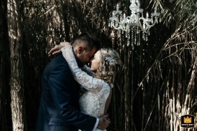 Antico Casale, Cesenatico, Italy, is the setting where the bride and groom stand closely together amid the lush green stalks of a dramatic bamboo bush on their wedding day.